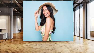 Portrait of cute summer brunette woman in hat and colorful dress, stylish girl have a fun and posing on blue background Wall mural