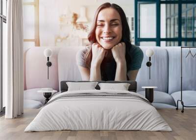 Portrait of smiling happy cute woman with closed eyes sitting on the couch at home Wall mural