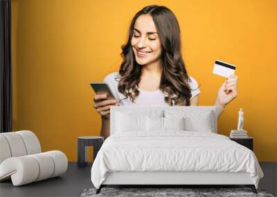 That was a breeze! A girl with a credit card in one hand and a mobile phone in other is showing her pleasant emotions and satisfaction because of using this devices. Wall mural