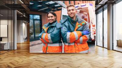 Two confident young doctors looking on the camera on ambulance and hospital background Wall mural