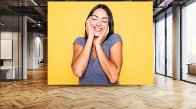 Young attractive cute brunette woman in gray T-shirt is posing and looking on camera isolated over yellow wall Wall mural