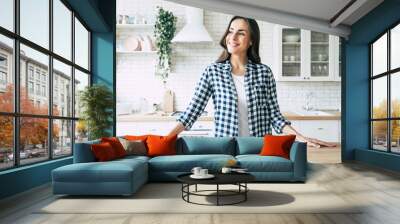 Young beautiful modern woman stands near table on kitchen at home. Wall mural