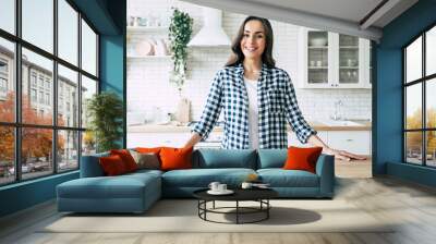 Young beautiful modern woman stands near table on kitchen at home. Wall mural