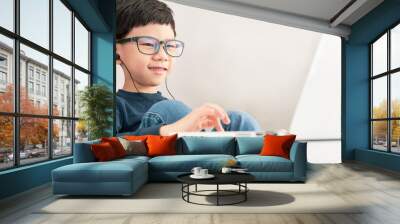 Online learning & Social distancing, Cute and happy Asian little boy click touchpad on computer laptop to study online lessons and gamification at home due to Covid-19 pandemic and school break. Wall mural