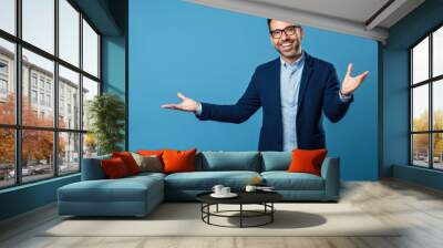 Cheerful businessman demonstrating something with copy space while standing on blue background Wall mural