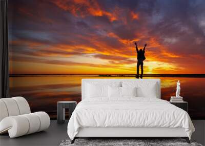 silhouette person against background beautiful sunset sky on ocean, reflection rays sun and sky in water. Freedom inspiration in nature under open sky enjoys beautiful view and meditates, happiness Wall mural