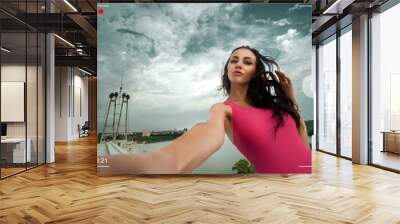 Beautiful brunette girl shoots video about herself with a smartphone, view through the viewfinder Wall mural