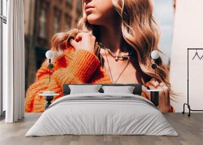 portrait of fashionable women in orange sweater and beige dress posing in the street Wall mural