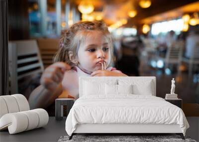 Litle girl is eating pasta in the restaurant. Wall mural