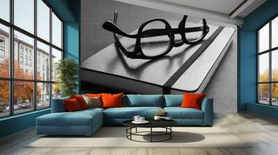 Closeup view of trendy black eyeglasses on trendy notebook. Wall mural