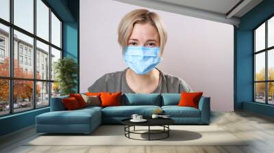 Girl with mask to protect her from Corona virus. Corona virus pandemic. woman wearing a face mask, looking at camera Wall mural