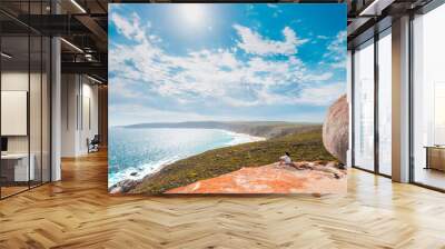 Woman sitting on the edge of the cliff at Remarkable Rocks on Kangaroo Island, South Australia Wall mural