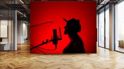 Silhouette of a beautiful girl with a red light singing into a studio microphone in a recording studio Wall mural