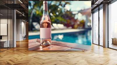 A bottle of rose wine with a blank mock-up label on the wooden table near the pool. Wall mural