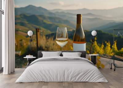 White wine in a bottle with a blank mock-up label on a wooden table outdoors overlooking the vineyards at sunset. Wall mural