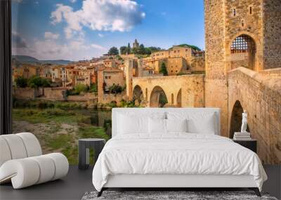 Besalu, Girona, Catalonia, Spain. Famous landmark. Old medieval Romanesque bridge Besalu over the river Fluvia on a sunny summer day. Wall mural