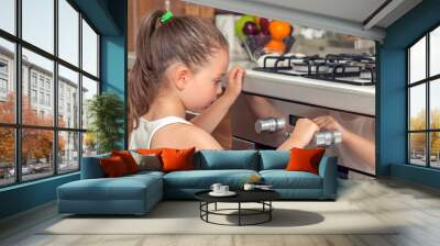 beautiful curious little girl examining oven in kitchen Wall mural