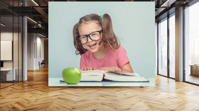 beautiful cute little girl with book and green apple having fun Wall mural