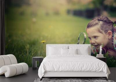 beautiful cute little girl with magnifying glass examining flower Wall mural