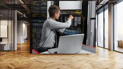 Young business man with laptop working in data center Wall mural