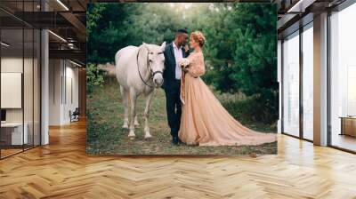 Newlyweds are standing near a white horse in nature, full height portrait Wall mural