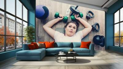 Tired fat woman lying on the floor in the gym Wall mural