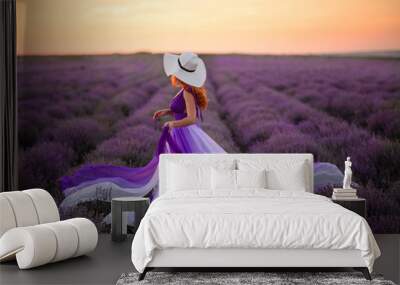 Young woman in luxurious purple dress standing in lavender field, rear view Wall mural