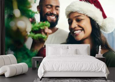 Christmas, tree and smile with a black couple decorating in the home together for the festive season. Love, celebration and holidays with a happy man and woman in a santa hat while bonding in a house Wall mural