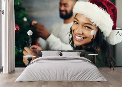 Couple, portrait and christmas tree decor together with love and care during the festive season. Husband, wife and hanging ornaments on an xmas tree while decorating with tinsel and bauble Wall mural