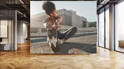 Fitness, city and woman stretching her legs in the street before a cardio workout, running or training. Sports, health and lady doing a warm up stretch for an outdoor exercise in the urban town road. Wall mural