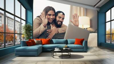 Hello from half way across the world. a young couple using a laptop to make a video call on the sofa at home. Wall mural