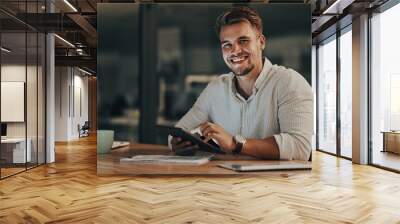 Im about to hit the deadline. Portrait of a young businessman using a digital tablet in an office at night. Wall mural