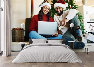 Laptop, credit card and couple online shopping for christmas gifts together sitting on the floor at home. Ecommerce, deals and young man and woman making sales purchase for xmas presents on computer. Wall mural