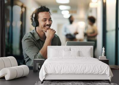 Listening is part of the planning process. a young businessman sitting in the office and wearing headphones while using his laptop for a virtual meeting. Wall mural