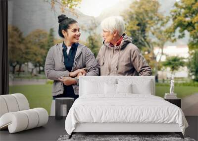 Senior woman, walker and nurse talking in a park with healthcare for elderly exercise. Walking, healthcare professional and female person with peace and physical therapy in a public garden with carer Wall mural