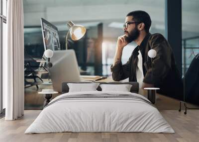 Serious productivity takes serious work. a young businessman using a computer during a late night in a modern office. Wall mural