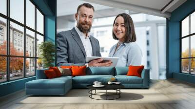 Bringing different expertise and perspectives together. Portrait of two businesspeople using a digital tablet together in an office. Wall mural