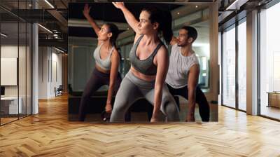 Getting in a full body workout. Full length shot of three young athletes working out with kettle bells in the gym. Wall mural