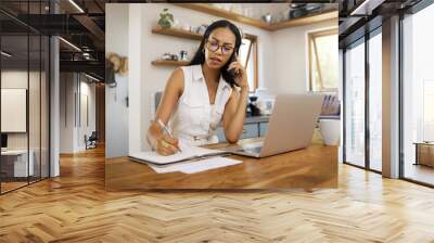 Business woman, professional and entrepreneur on phone call talking while working remote on laptop in home. Freelancer answering to chat, network and consulting while planning notes Wall mural