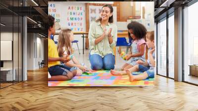 Diversity, teacher with children at school and in a classroom with a lens flare. Education or learning, happiness and smile with female person with kindergarten kids playing together in a class Wall mural