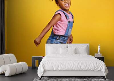 Excited, jump and happy girl child jumping in happiness, joy and smile while isolated in a studio yellow background. Energy, celebrate and kid in the air due to winning, celebrating and succuss Wall mural