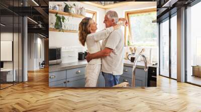 Happy senior couple, love and care embracing relationship bonding together in the kitchen at home. Elderly man and woman hugging, relaxing and enjoying a holiday break of romance in happiness indoors Wall mural