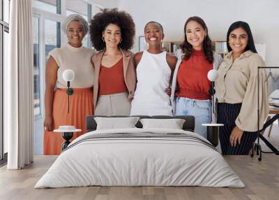 Portrait of a diverse group of smiling ethnic business women standing together in the office. Ambitious happy confident professional team of colleagues embracing while feeling supported and empowered Wall mural