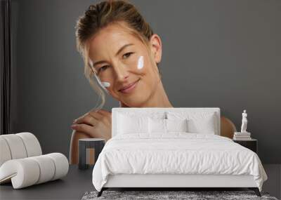 Skincare, beauty and woman with face product for a morning facial healthcare and wellness routine in studio. Smile, relax and mature model happy to show her selfcare dermatology cosmetics and cream Wall mural