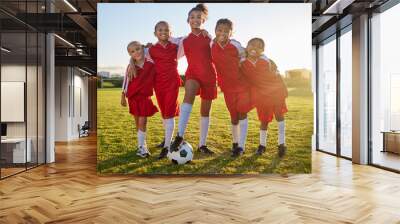 Soccer, team sports and portrait of children training for football game on a grass field together. Happy, smile and young group of girl athletes in partnership and teamwork for sport match at school Wall mural