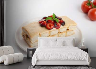 Stacked pastry with cherry and mint garnish on white plate. Wall mural