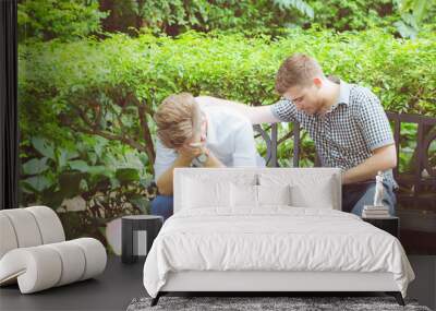 American businessmen consoling friend. Frustrated young man being consoled by his friend in garden. Wall mural