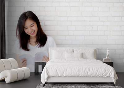 Beautiful of portrait young asian woman happiness relax standing reading book on concrete cement white background at home, girl happy study content literature, education and lifestyle concept. Wall mural