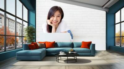 Beautiful portrait asian woman working online laptop lying on floor brick cement background, freelance girl using notebook computer with connect to internet for job, business and lifestyle concept. Wall mural