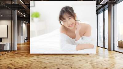 Beautiful portrait young asian woman lying and smile while wake up with sunrise at morning, beauty cute girl happy and cheerful resting on bed in the bedroom, lifestyle and relax concept. Wall mural